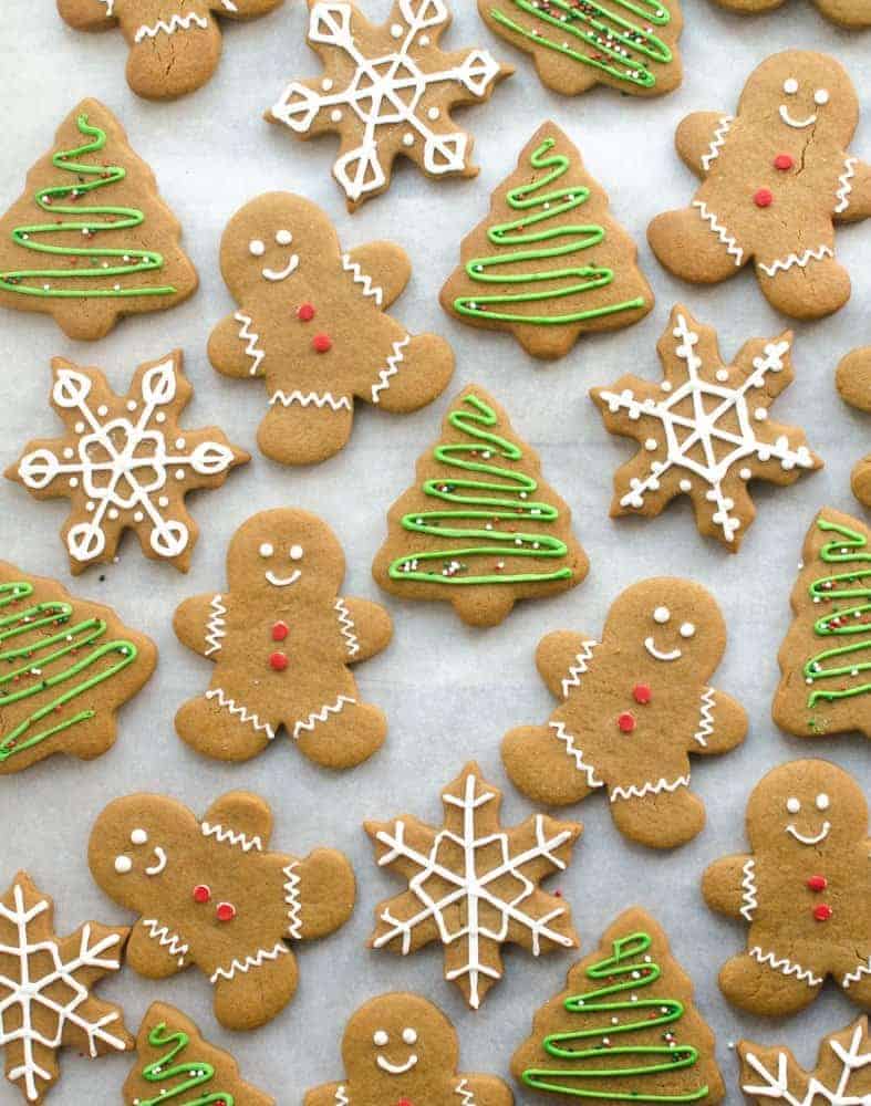 Gingerbread cookies that are shaped like men, trees, and snowflakes on a white background