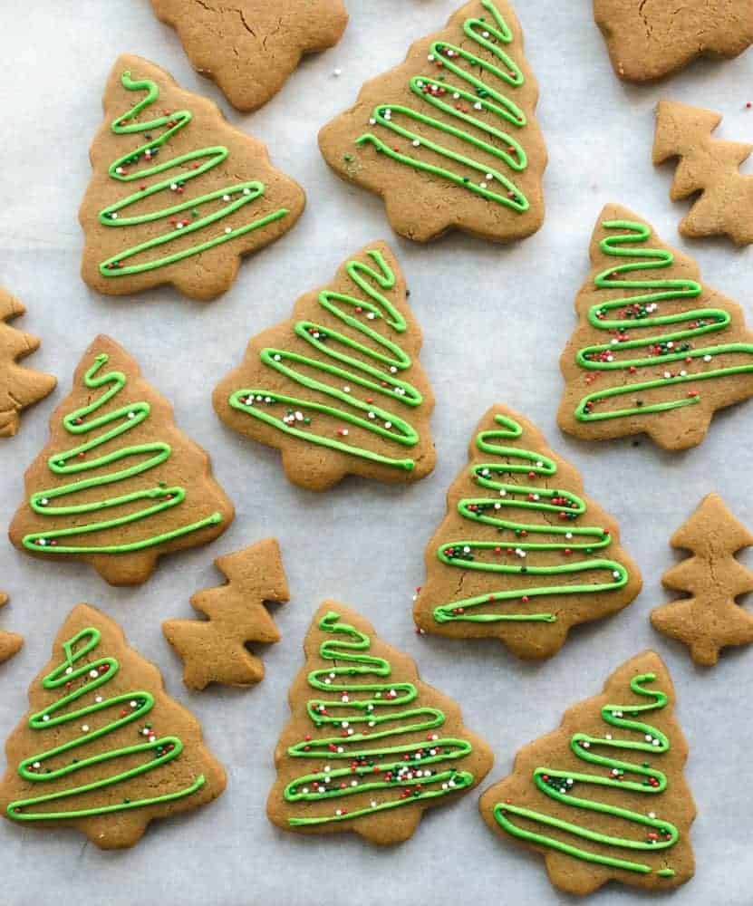 gingerbread cookies cut out like trees and decorated with green icing and sprinkles on white paper