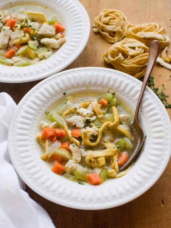Two white bowls of chicken noodle soup