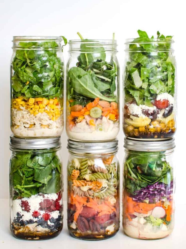 Six mason jars filled with different colorful layered salads