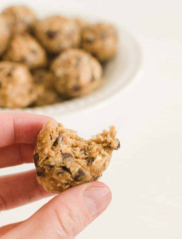 These Peanut Butter Chocolate Chip Oatmeal Energy Bites are perfect for snacks, dessert, lunch boxes, or post-workout recovery time. A hand holding a Peanut Butter Chocolate Chip Oatmeal Energy Ball with a bite taken out of it.