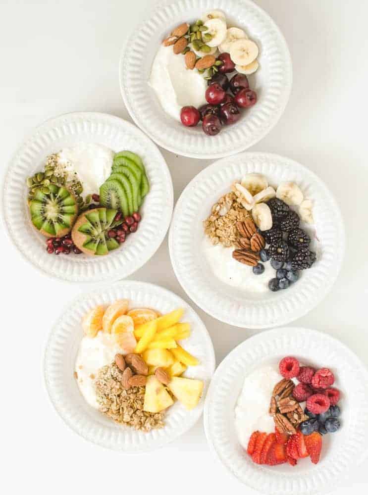 five round white bowls filled with instant pot yogurt and fruits nuts and granola