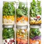 Six mason jars filled with different colorful layered salads