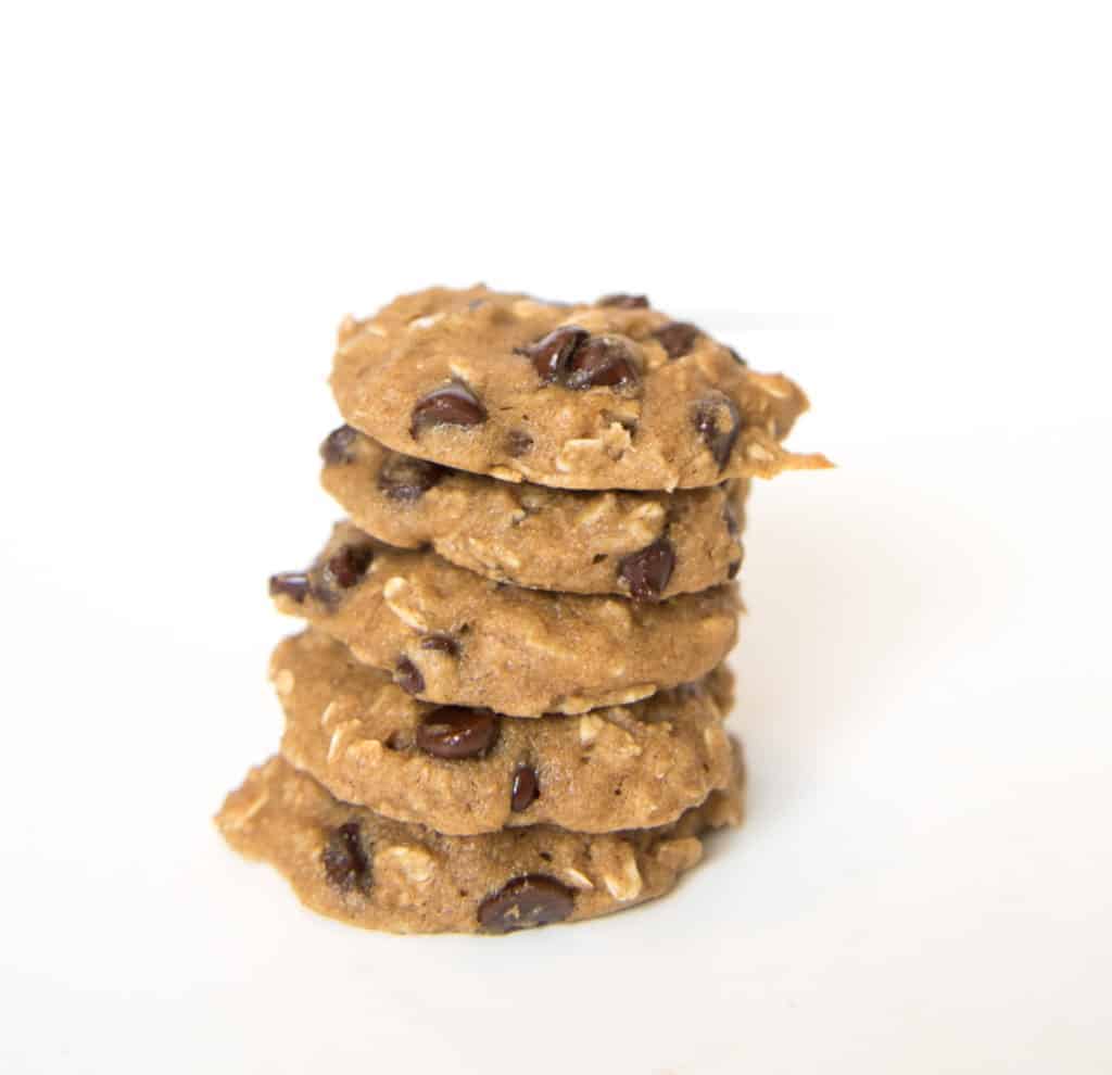 A stack of five applesauce oatmeal cookies with chocolate chips is arranged on a white surface against a plain white background.