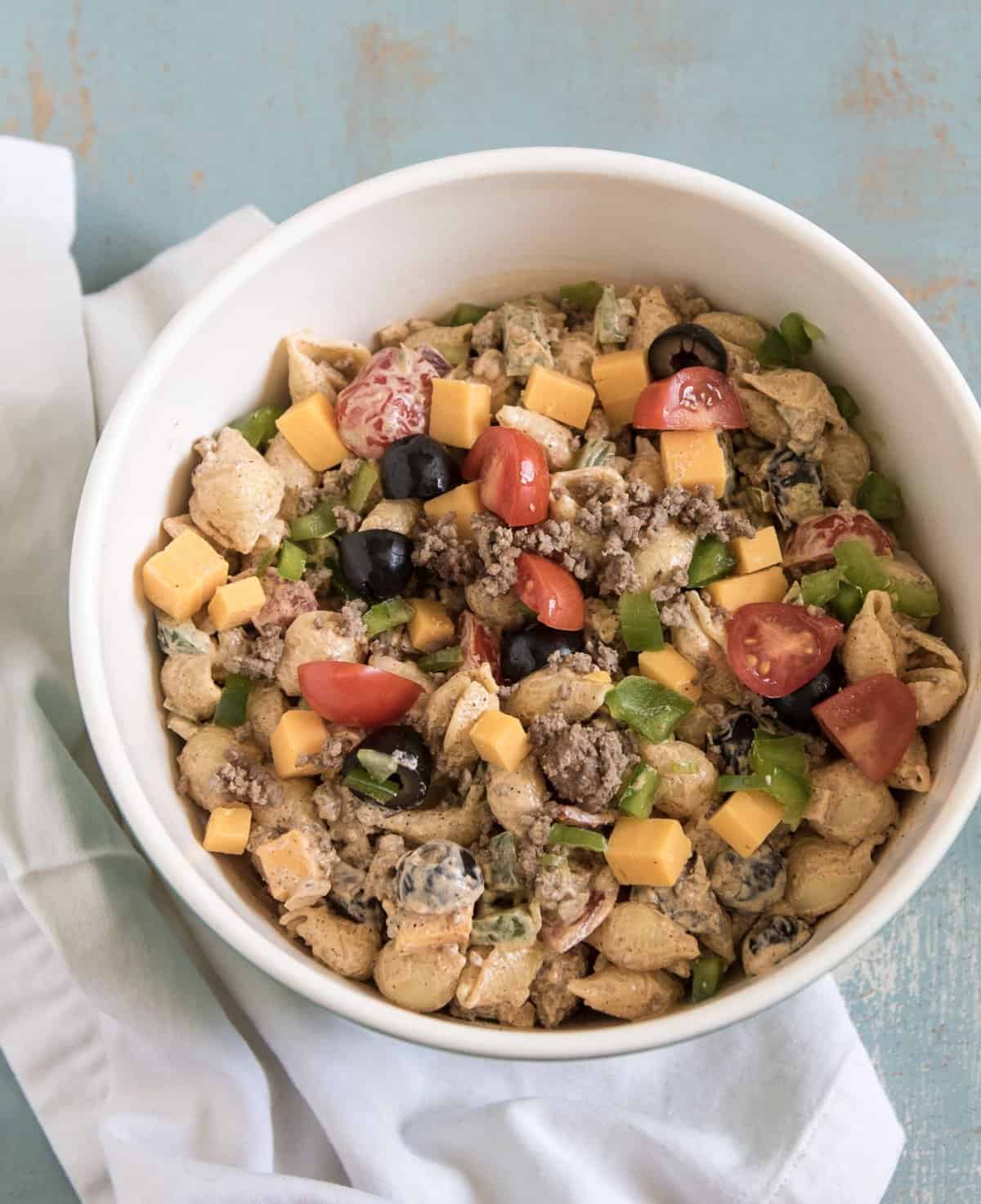 Creamy taco pasta salad made with pasta, hamburger, chopped vegetables, and a creamy taco inspired dressing to bring it all together. Bonus: It's done in about 20 minutes!