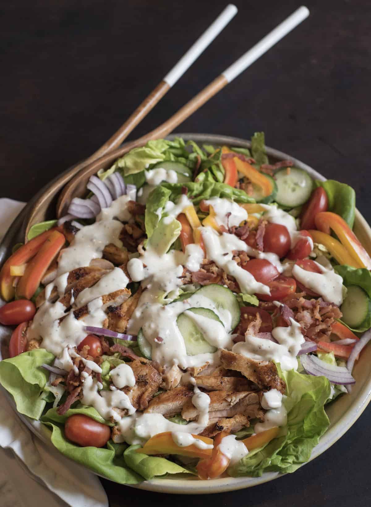 The BEST Chicken Bacon Ranch Salad of summer is a main dish green salad topped with all of your favorite things such as pan seared chicken, bacon, tomatoes, cucumber, and plenty of ranch dressing!