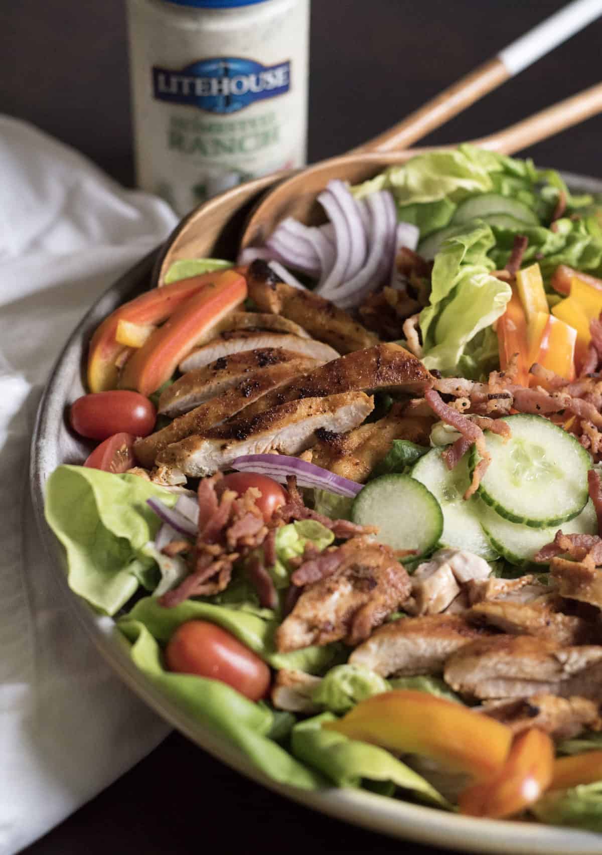 The BEST Chicken Bacon Ranch Salad of summer is a main dish green salad topped with all of your favorite things such as pan seared chicken, bacon, tomatoes, cucumber, and plenty of ranch dressing!