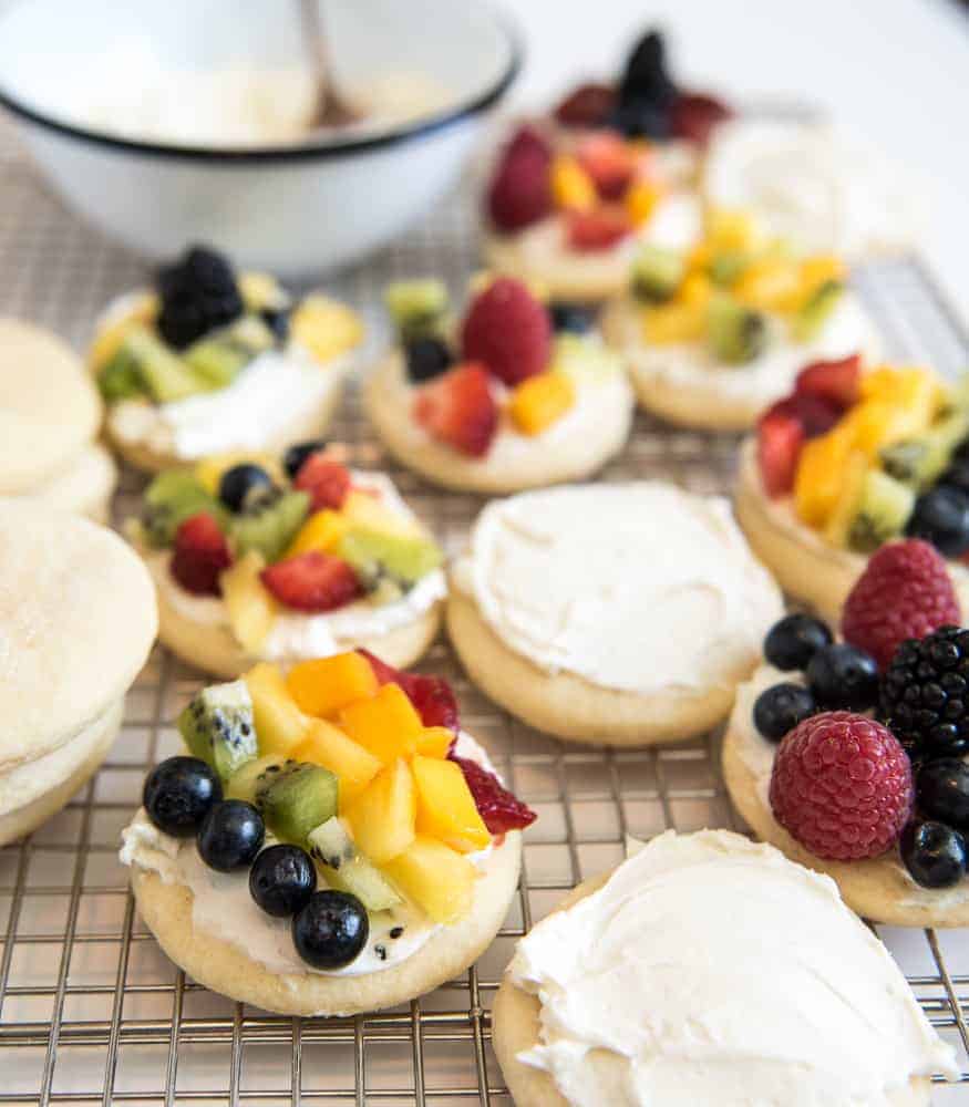 Festive fruit pizza cookies are made with super soft sour cream sugar cookies & a simple cream cheese frosting, & then piled high with seasonal fruit.