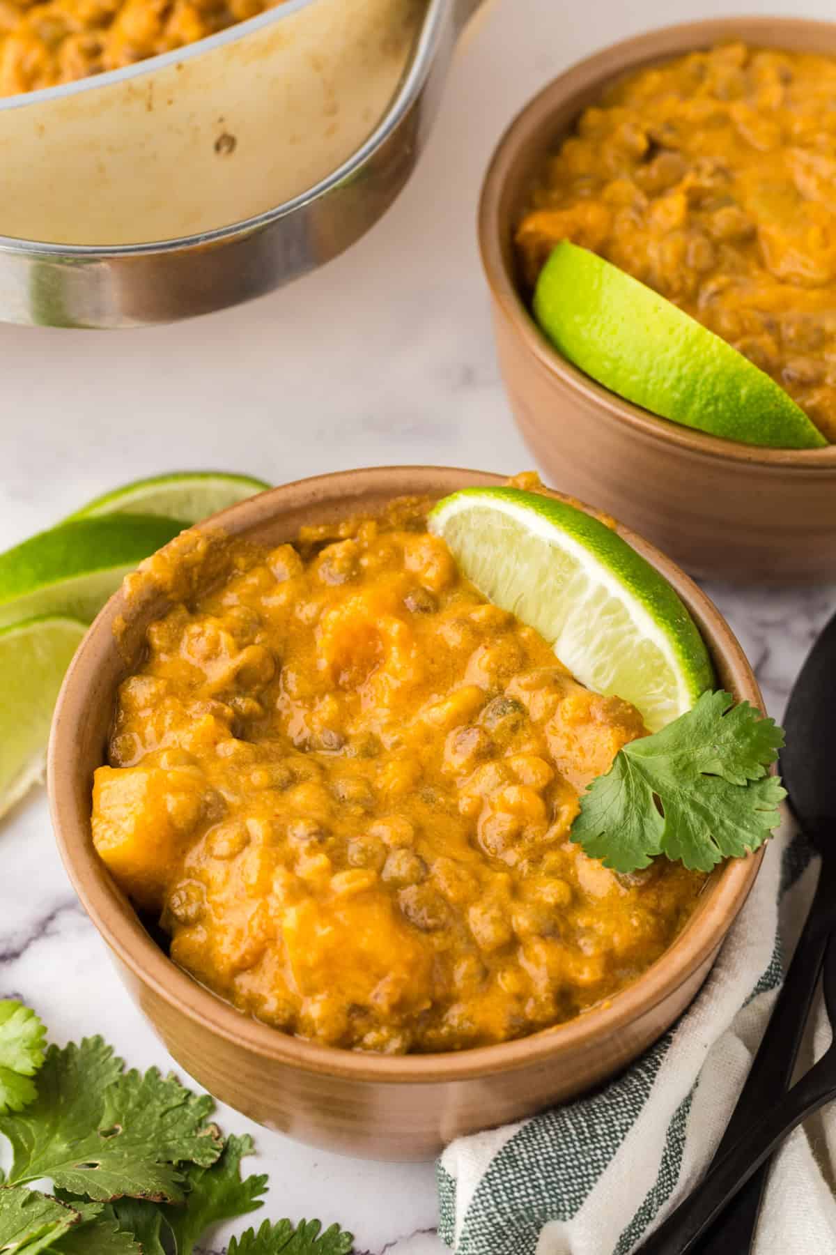 wooden serving bowl with Lentil curry with butternut squash and limes.