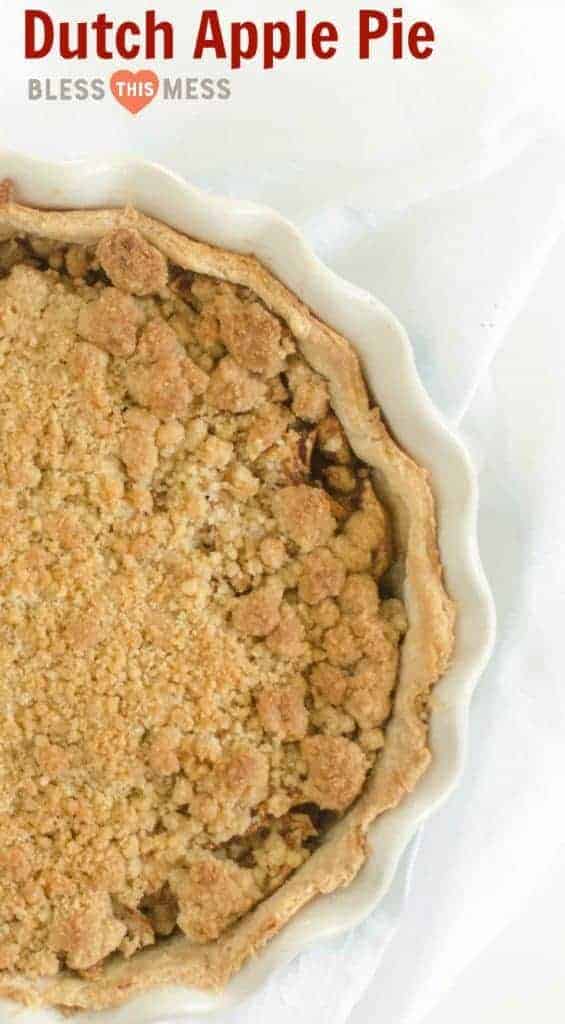 Top view of a Dutch apple pie in a white pie dish, topped with golden-brown streusel, inviting anyone to recreate this deliciousness. The light fabric background enhances the charm, while text at the top reads Dutch Apple Pie and Bless This Mess, begging you to try this mouthwatering Dutch apple pie recipe.