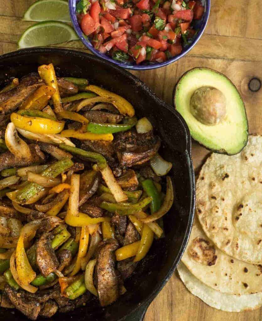 sauteed mushrooms and peppers in a cast iron pan with tortillas and salsa to the side