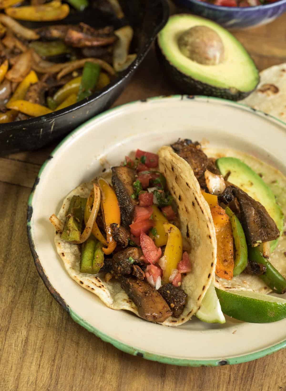 tacos on a plate with an avocado to the side