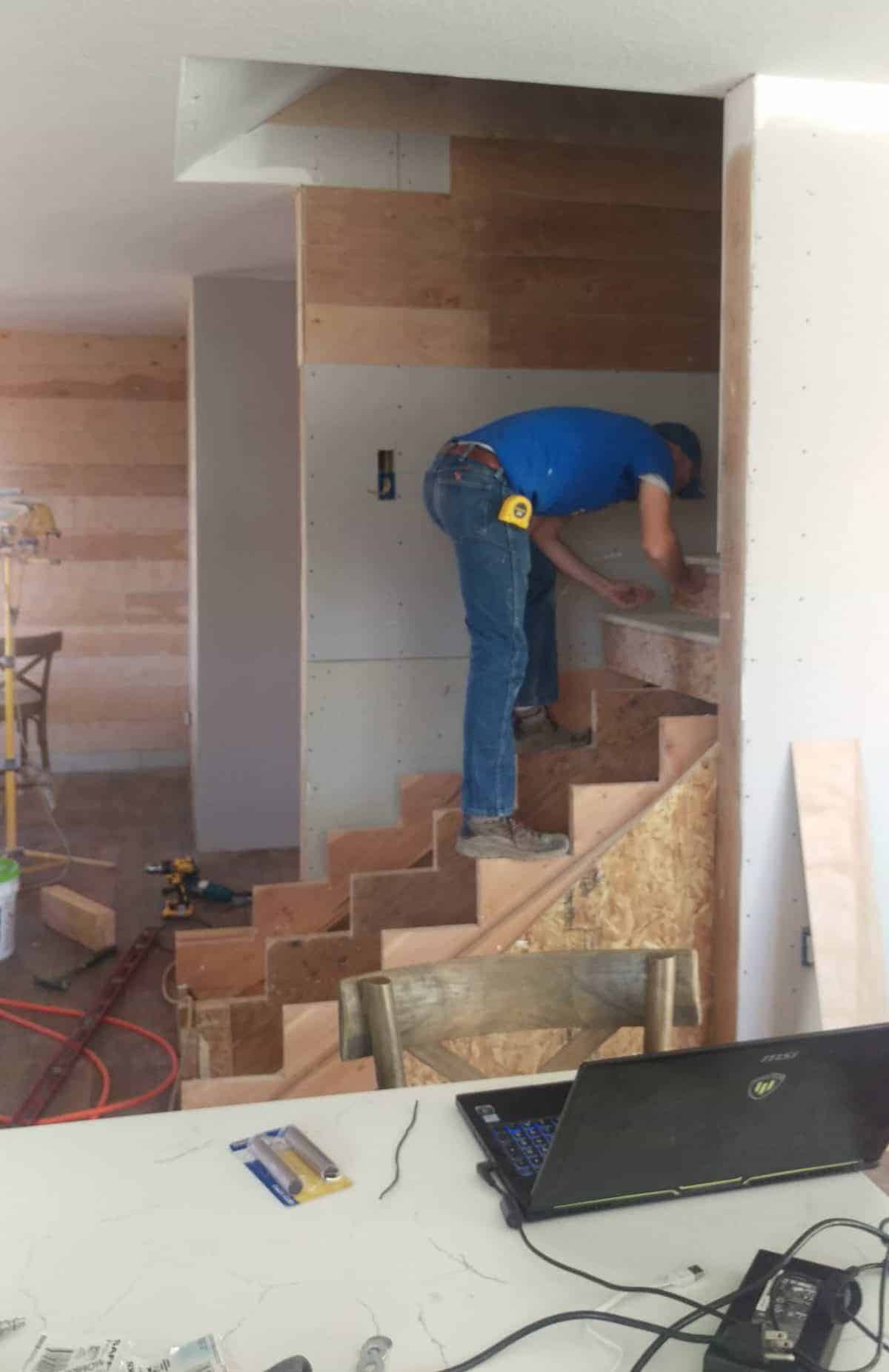 a man installing stairs while standing on narrow steps to work