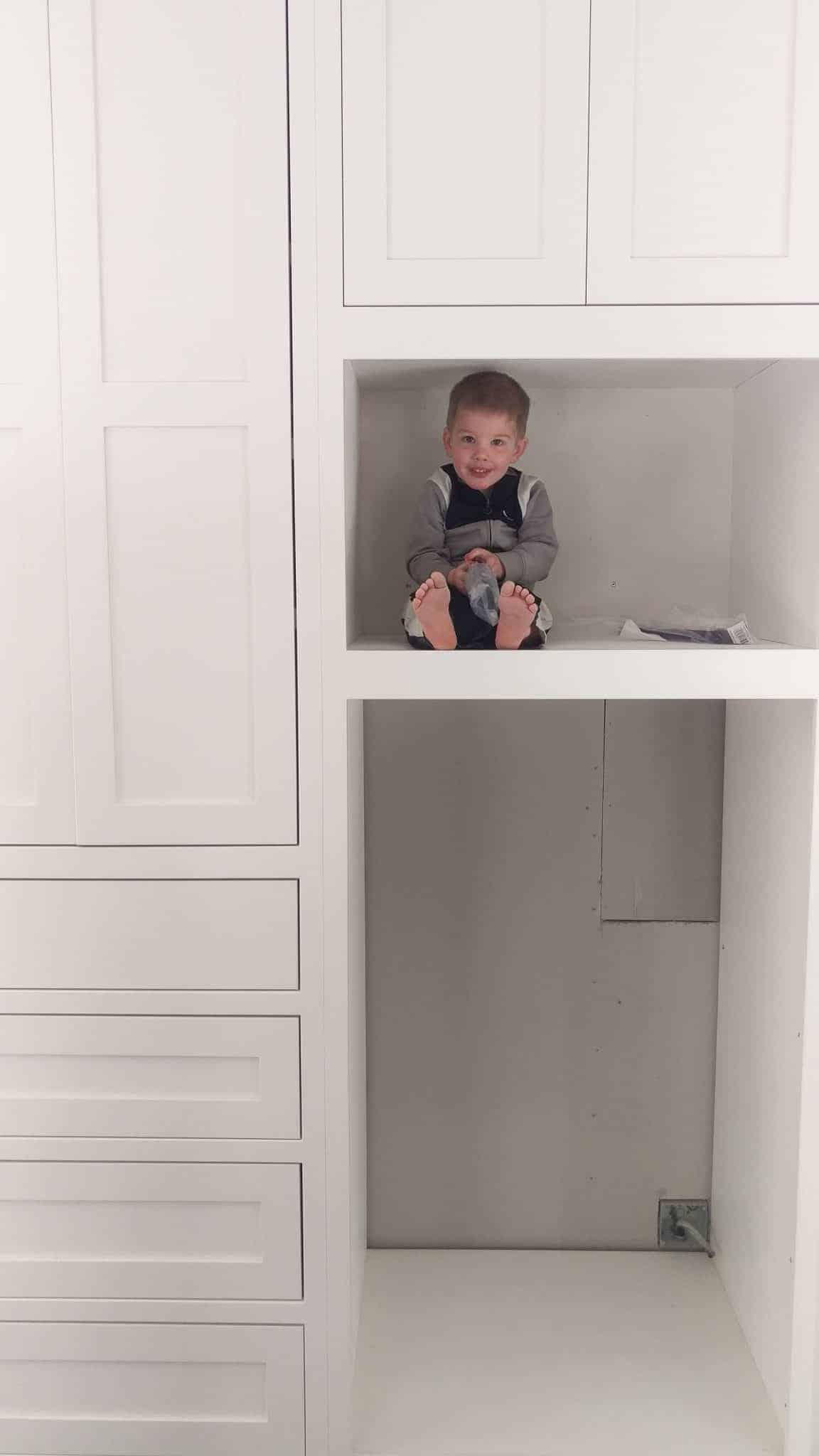 a toddler sitting inside the installed cabinets