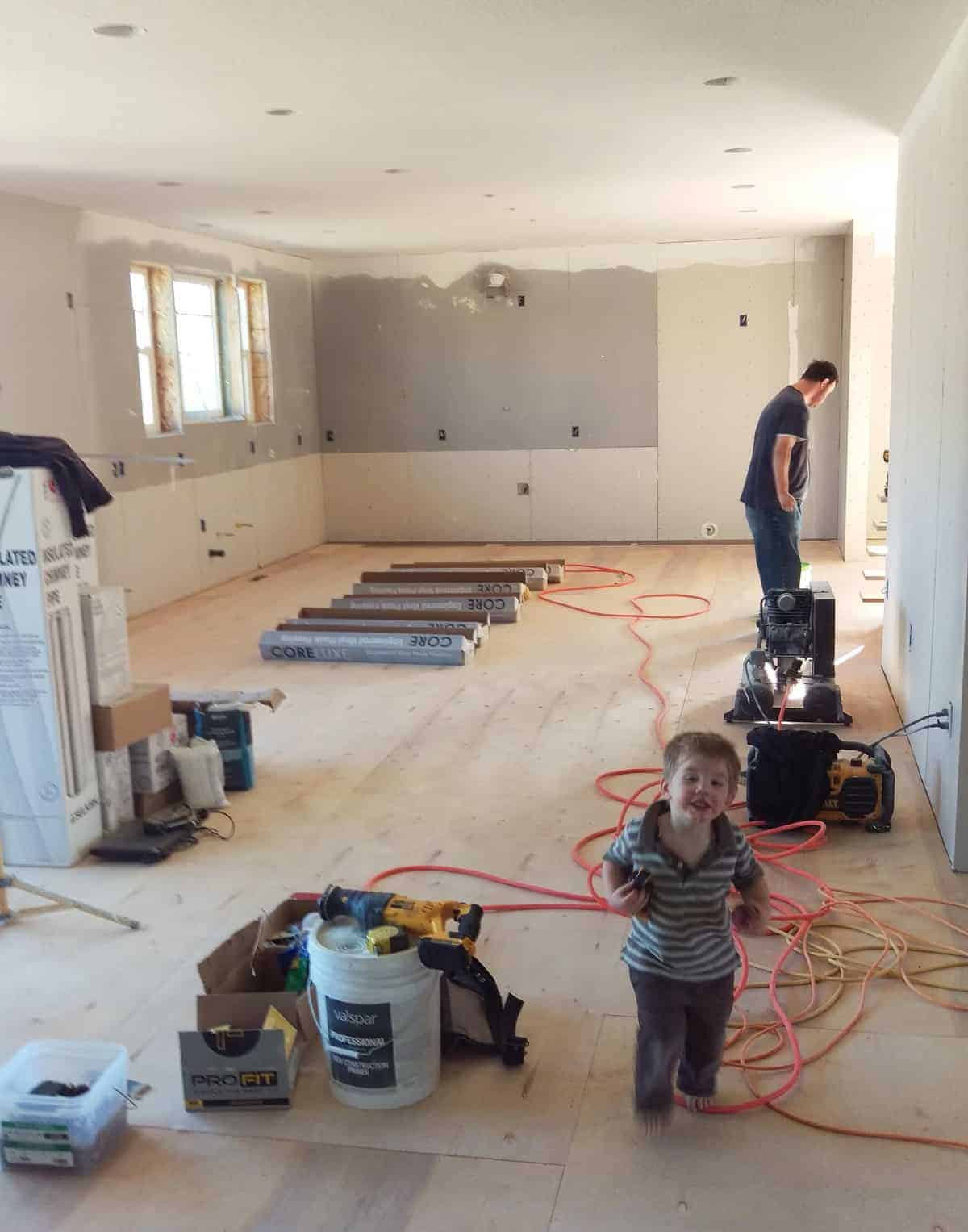 drywall being painted and a toddler running around on a wooden subfloor