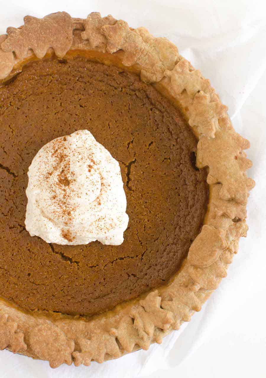 pumpkin pie with a dollop of whipped cream and cinnamon sprinkled on top