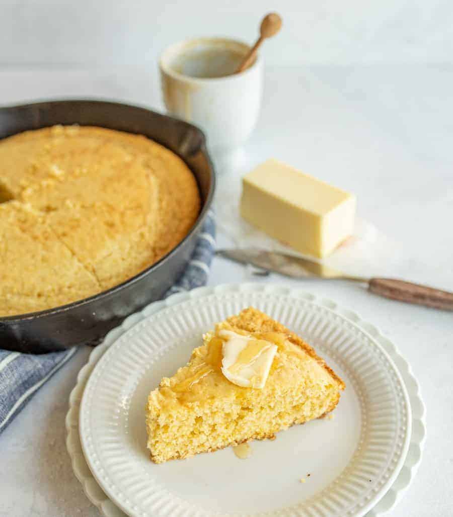 slice of cornbread on plate with honey and butter on top