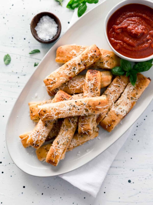 Plate of cheesy pizza sticks and cup of sauce