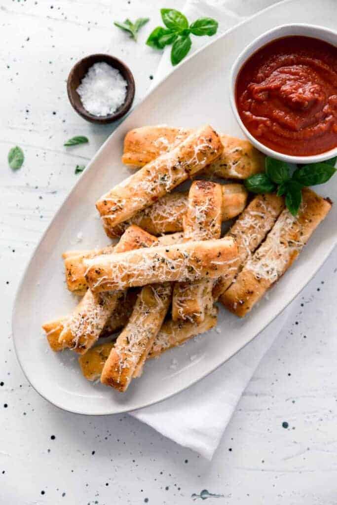 Plate of cheesy pizza sticks and cup of sauce