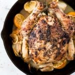 Image of a whole baked chicken in a pan with halved lemons