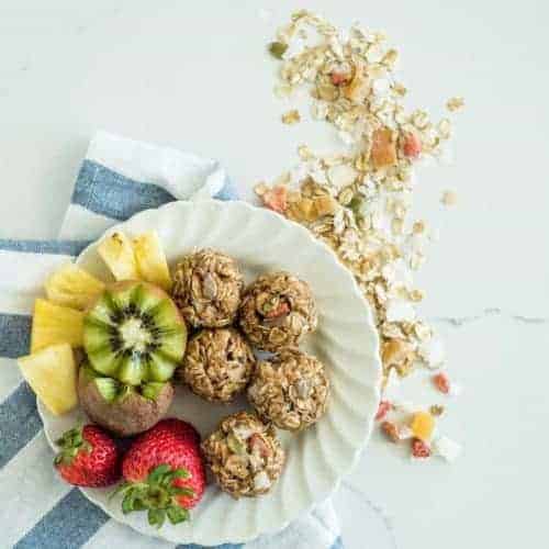 A plate with 3-ingredient muesli bites with whole strawberries, halved kiwi and pineapple chunks