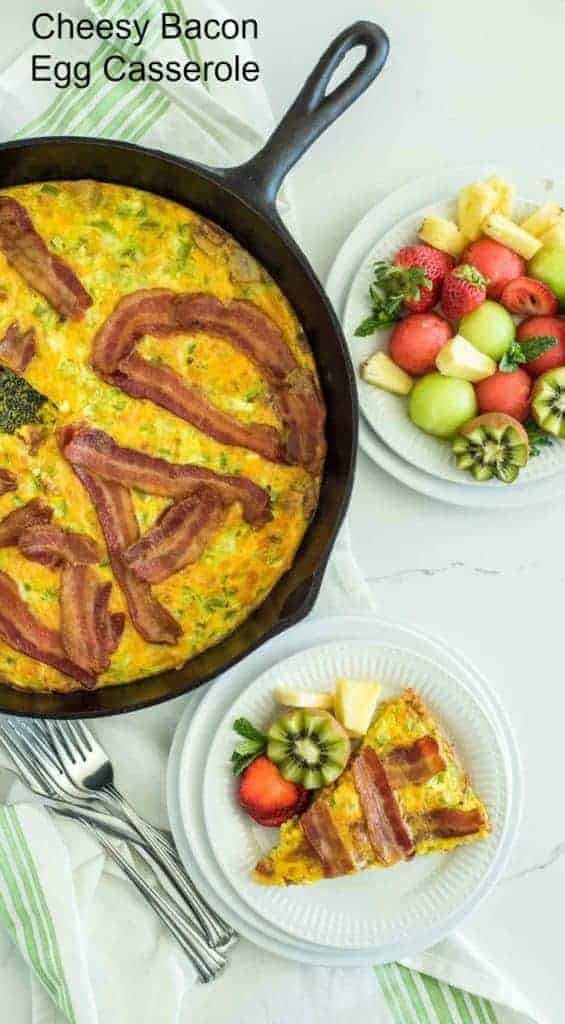 Title Image for Cheesy Bacon Egg Casserole, a round white plate with a slice of cheesy bacon egg casserole and fresh fruit, a cast-iron skillet of cheesy bacon egg casserole and a round white plate of fresh fruit