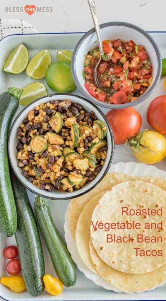 Tortilla shells, whole zucchini, yellow tomatoes, lime wedges, a bowl of corn with black beans and zucchini, a bowl of fresh salsa