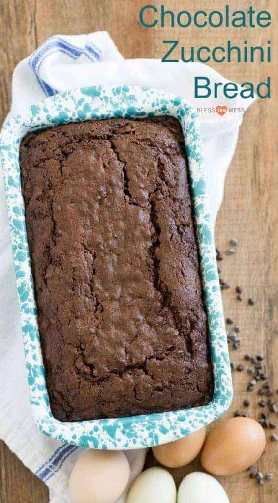 Title Image for Chocolate Zucchini Bread and a loaf pan of chocolate zucchini bread on a wooden board with a tea towel, eggs, and mini chocolate chips