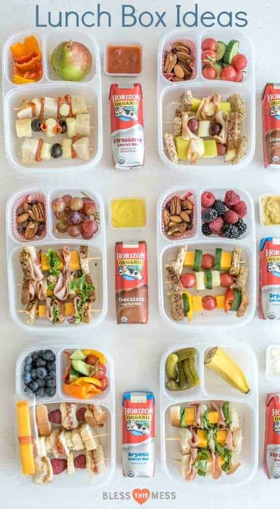 Six divided lunch containers with a variety of sandwiches on a stick, assorted vegetables and fruits and Horizon Organic Milk boxes