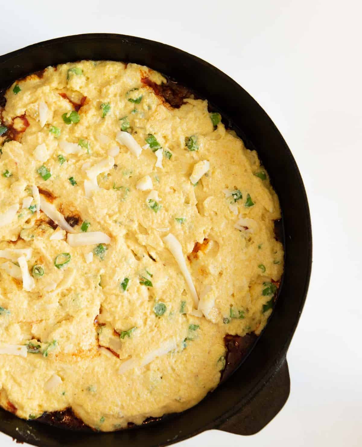 One Pan Tamale pie is made with a rich meat and vegetable filling topped with a golden cornbread crust that has cheese and green onions in it, all made in one skillet. 