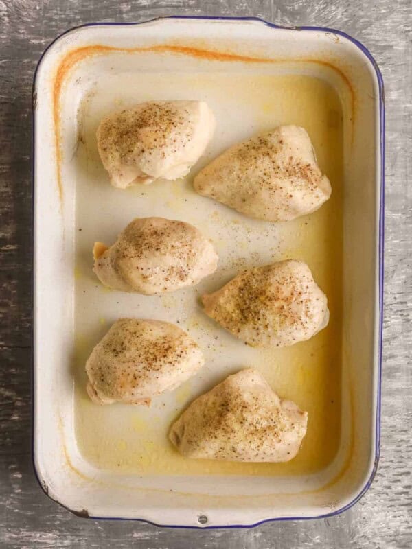 Title Image for 8 Secrets to the BEST baked chicken and a baking dish with seasoned baked chicken breasts