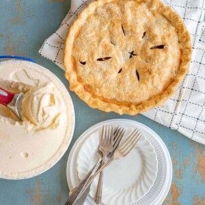 apple pie with ice cream and white plate with fork and spoon.