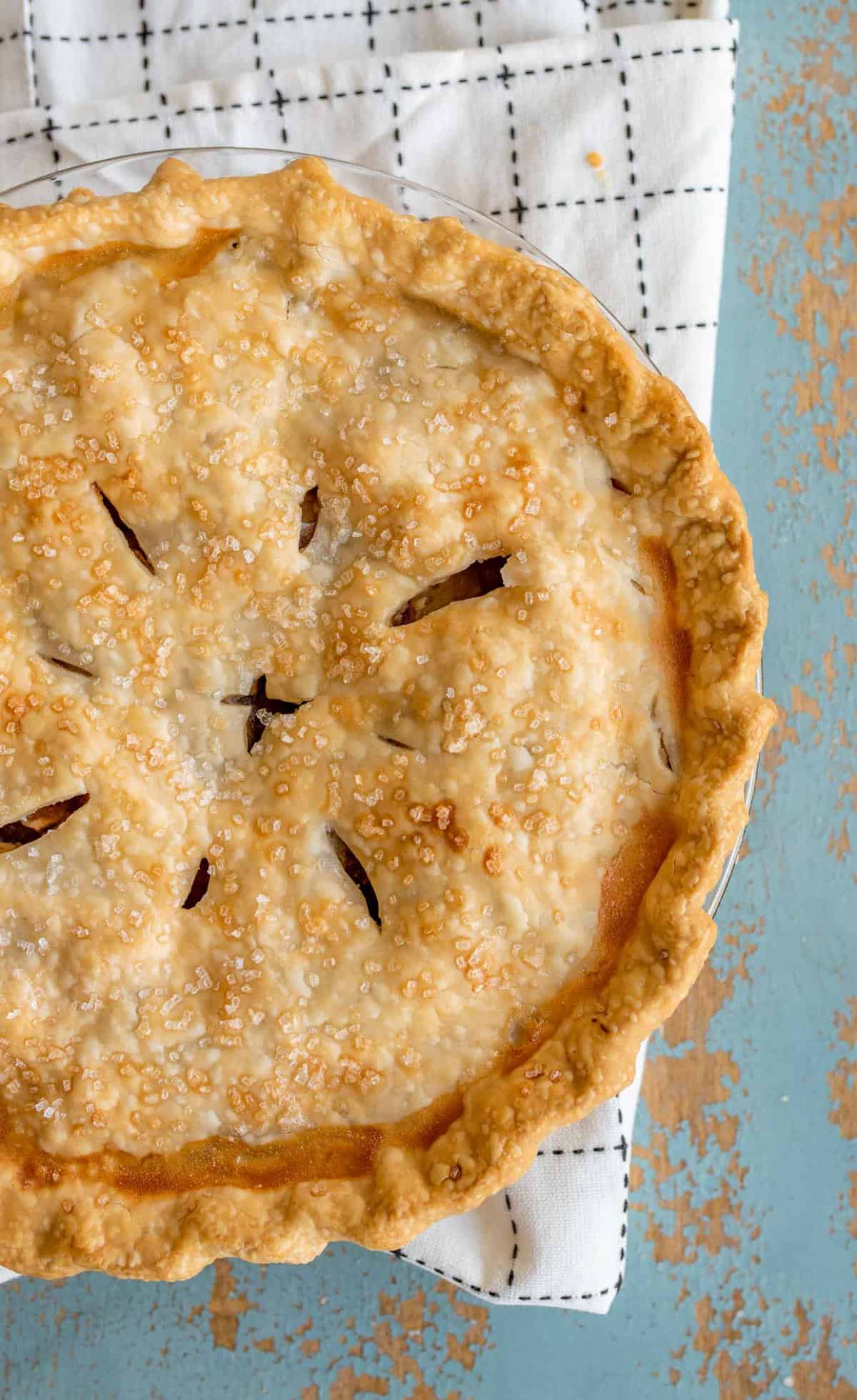 whole apple pie, cooked and golden brown with pieces of sugar on top