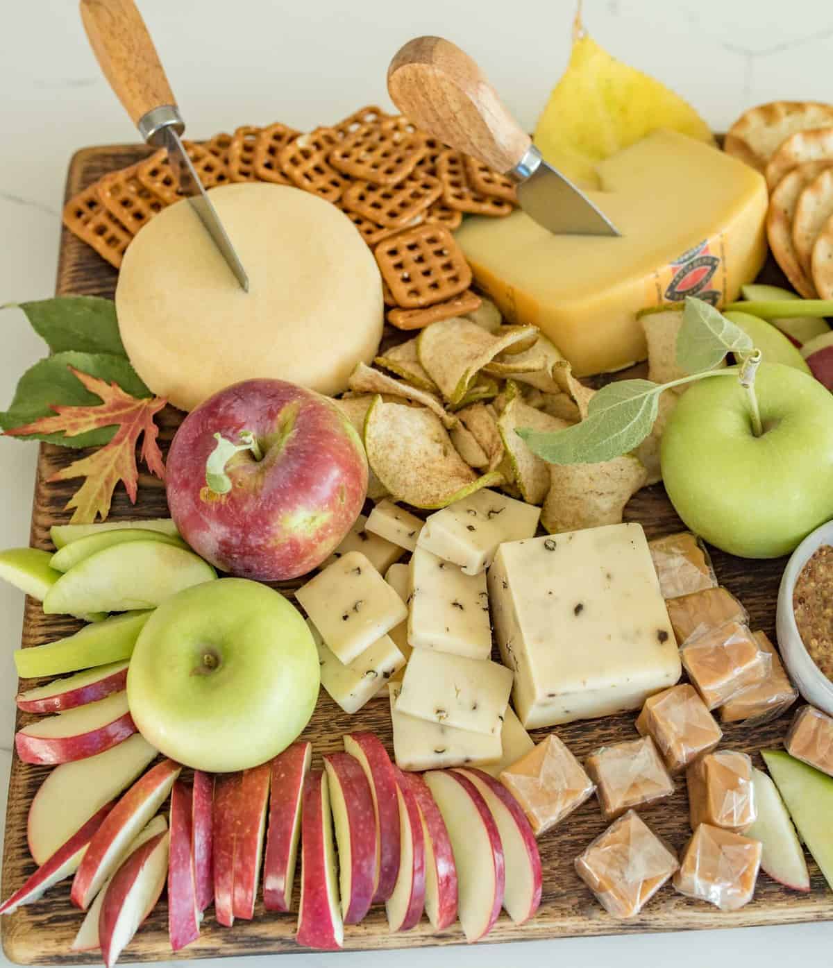 Platter with cheese, apple slices, crackers, and caramel dip
