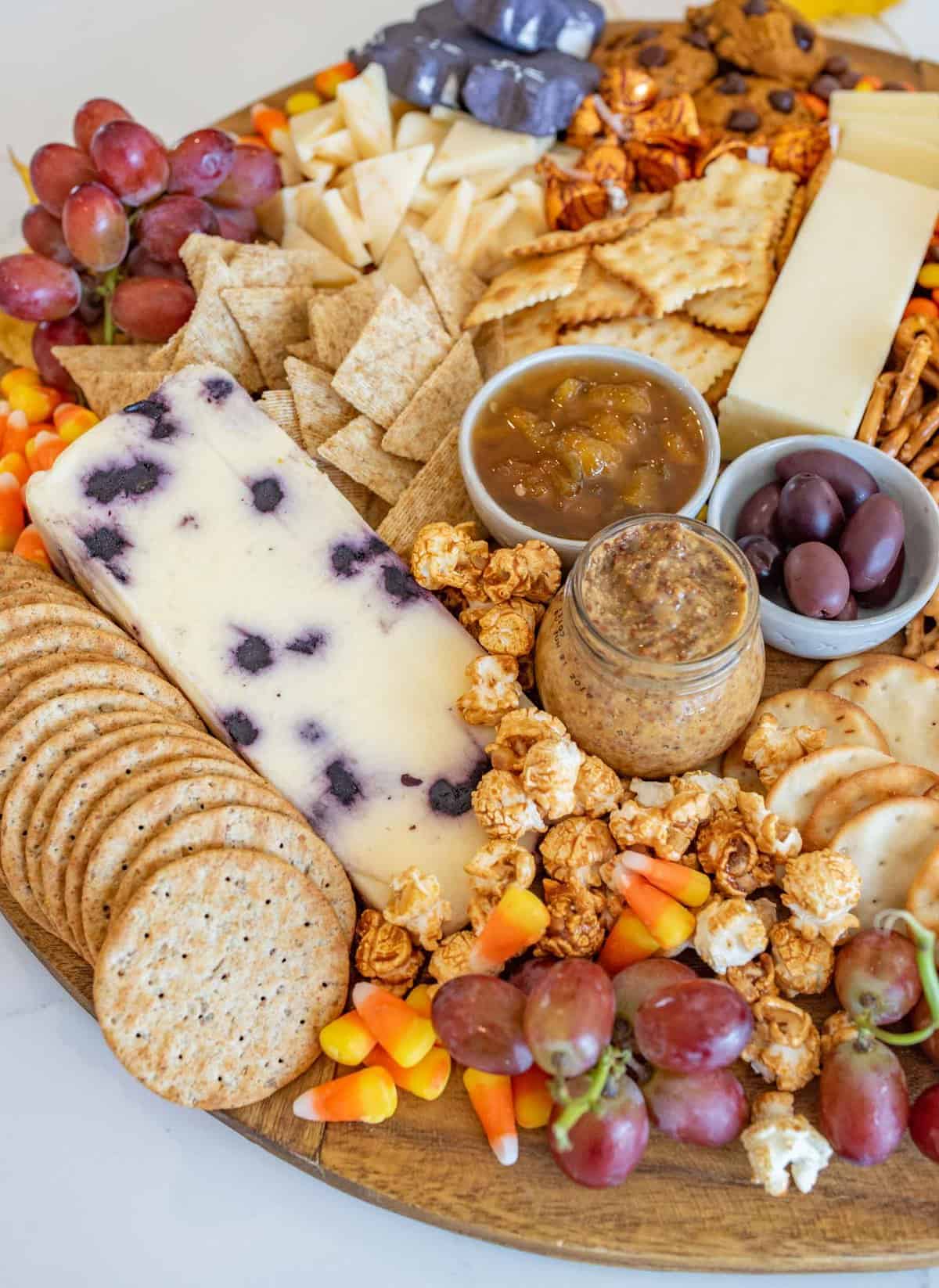 Fun and festive Halloween Cheese board made with simple cheese, crackers, pumpkins for garnish, and or coarse, lots of Halloween candy. 