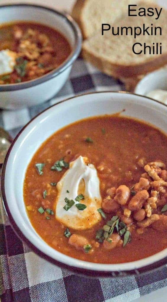 A bowl of Easy Pumpkin Chili garnished with sour cream and fresh herbs