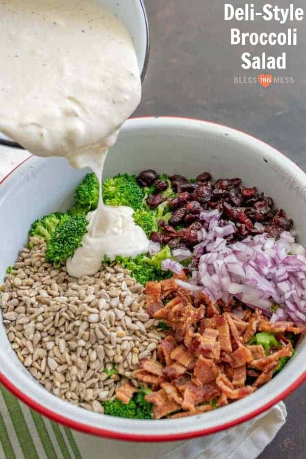 Title Image for Deli Style Broccoli Salad and a serving bowl with separate broccoli salad ingredients, including broccoli, bacon, diced red onion, dried cranberries, sunflower seeds and a creamy dressing