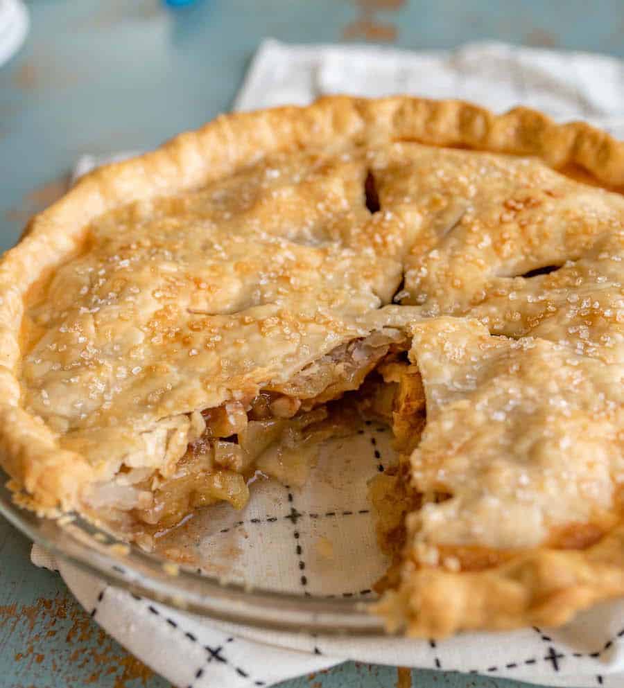 whole apple pie in a glass pie plate with only one slice missing