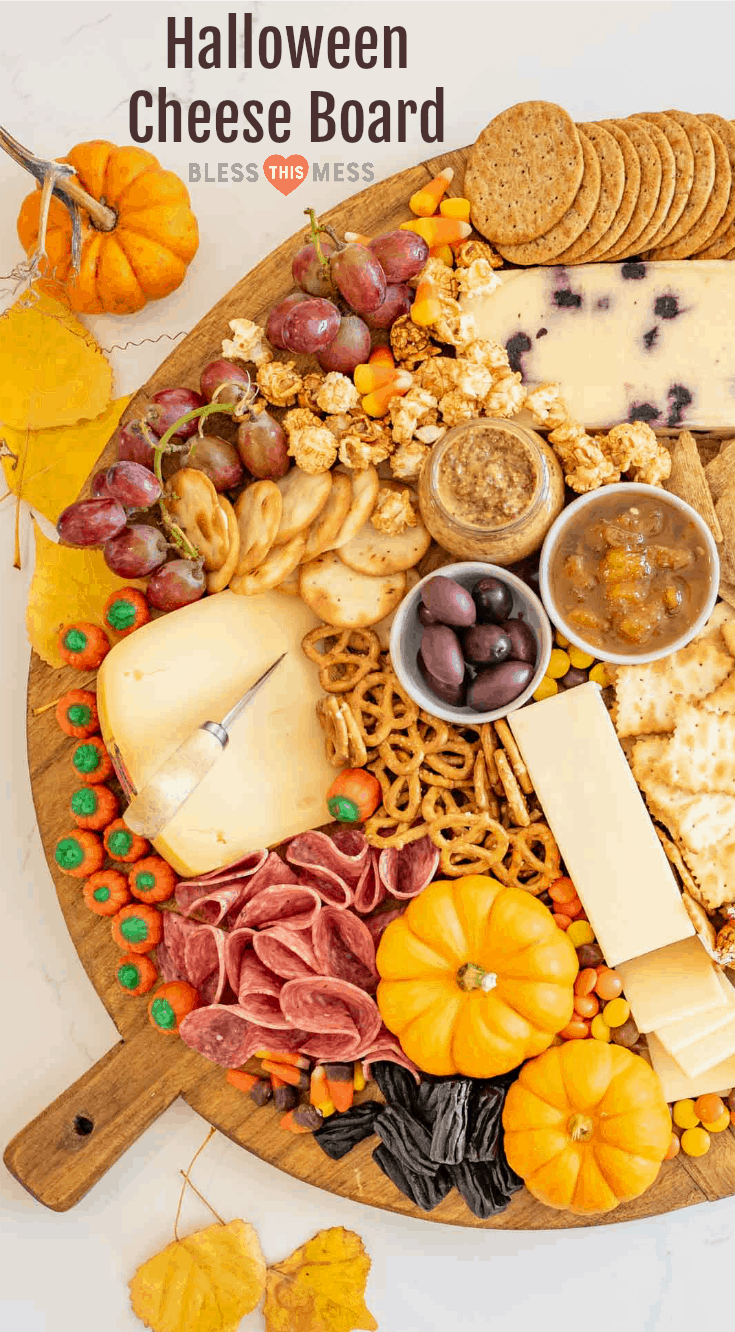 Fun and festive Halloween Cheese board made with simple cheese, crackers, pumpkins for garnish, and or coarse, lots of Halloween candy. 