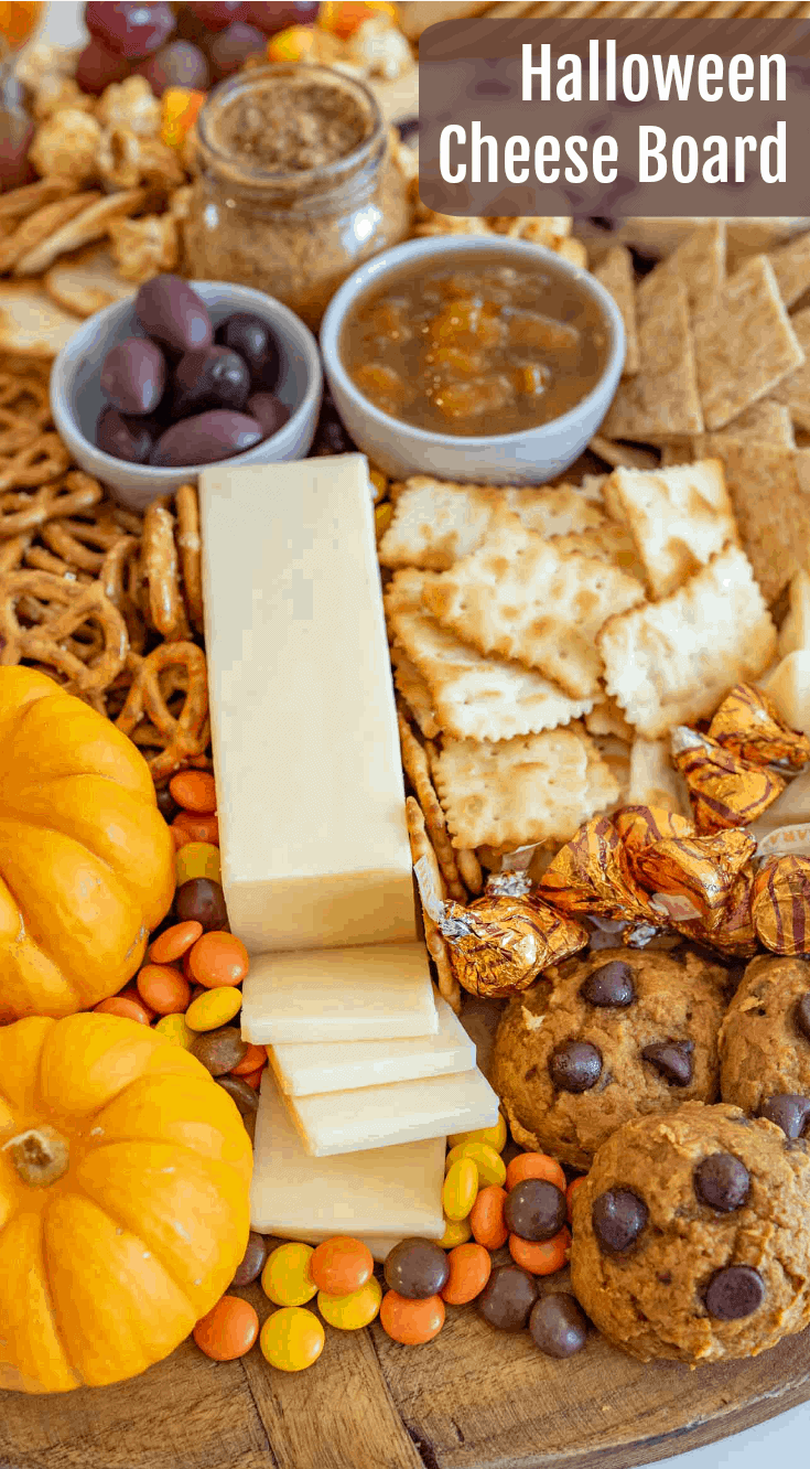 Fun and festive Halloween Cheese board made with simple cheese, crackers, pumpkins for garnish, and or coarse, lots of Halloween candy. 