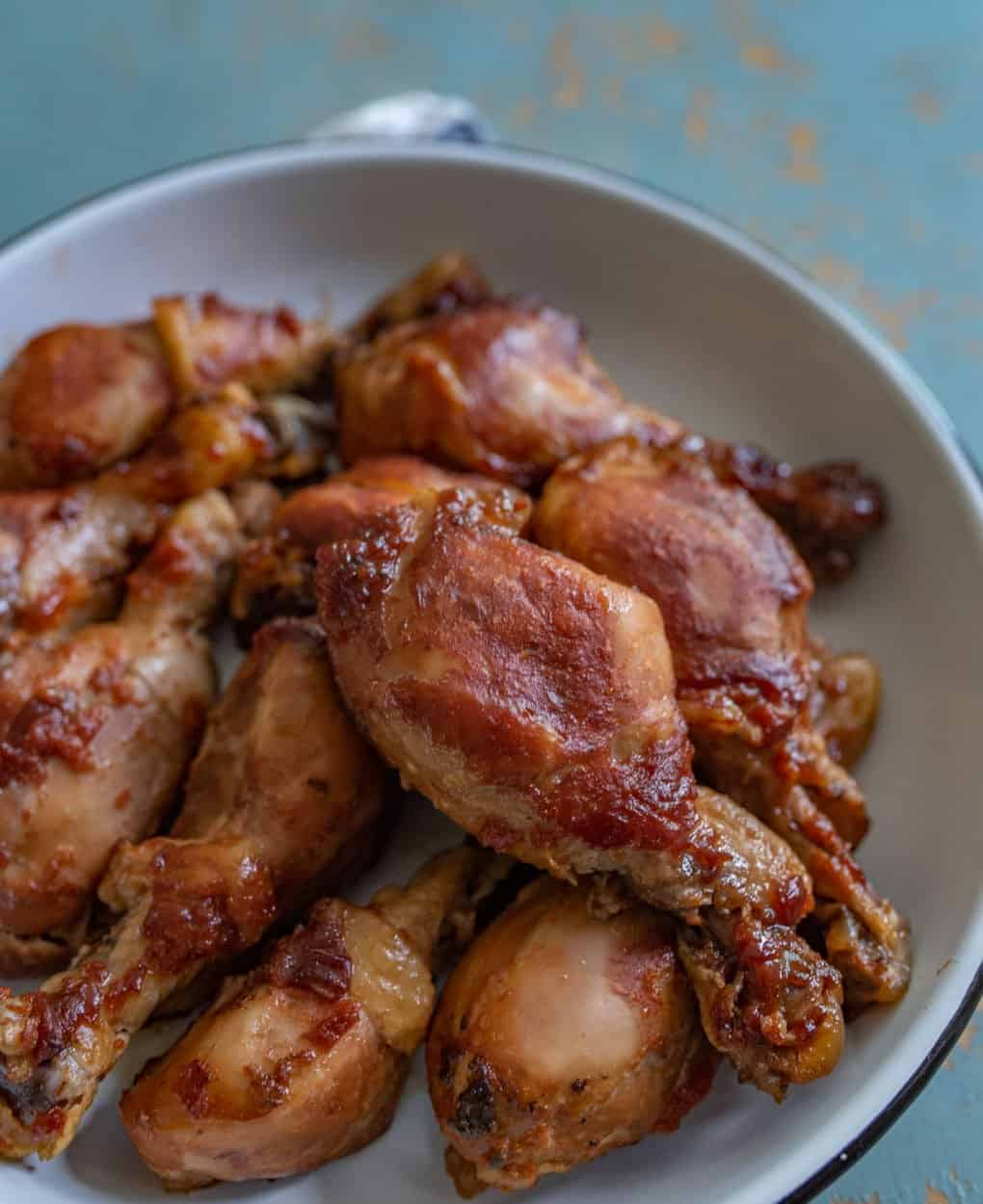 cooked chicken legs with red sauce on white plate