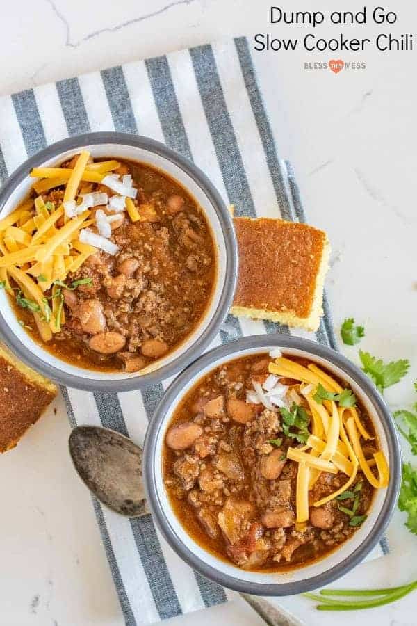 Title Image for Dump and Go Slow Cooker Chili and two bowls of chili topped with shredded cheese, diced onion and cilantro