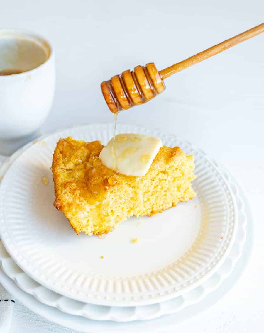 Skillet Cornbread with butter and honey drizzle on round white plate