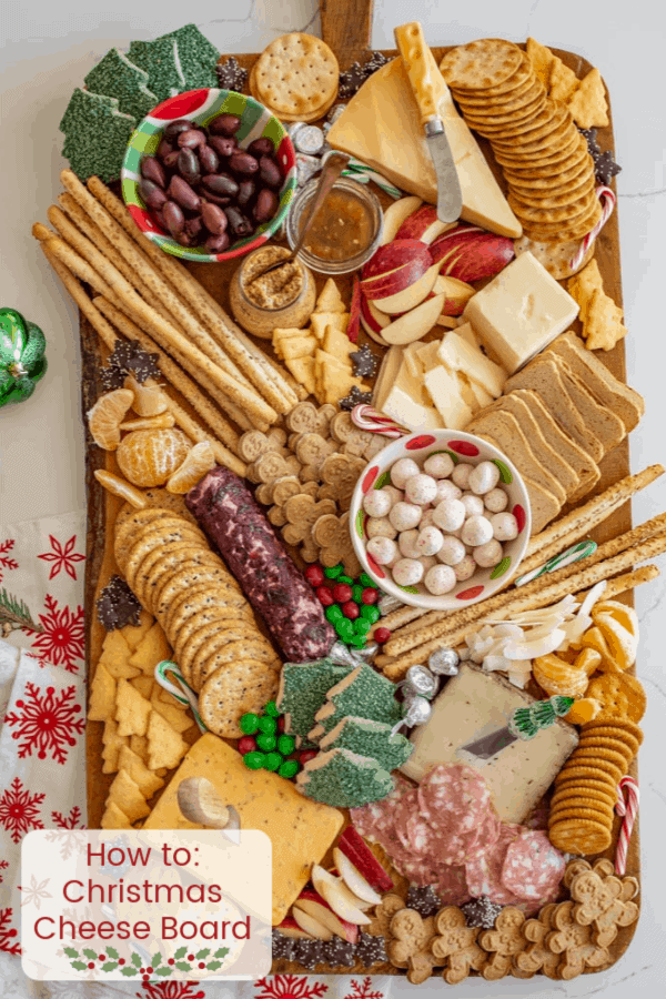 Title Image for How to: Christmas Cheese Board and a large wooden board of Christmas cookies, candy canes, crackers, meats, cheeses, olives, apples, and spreads