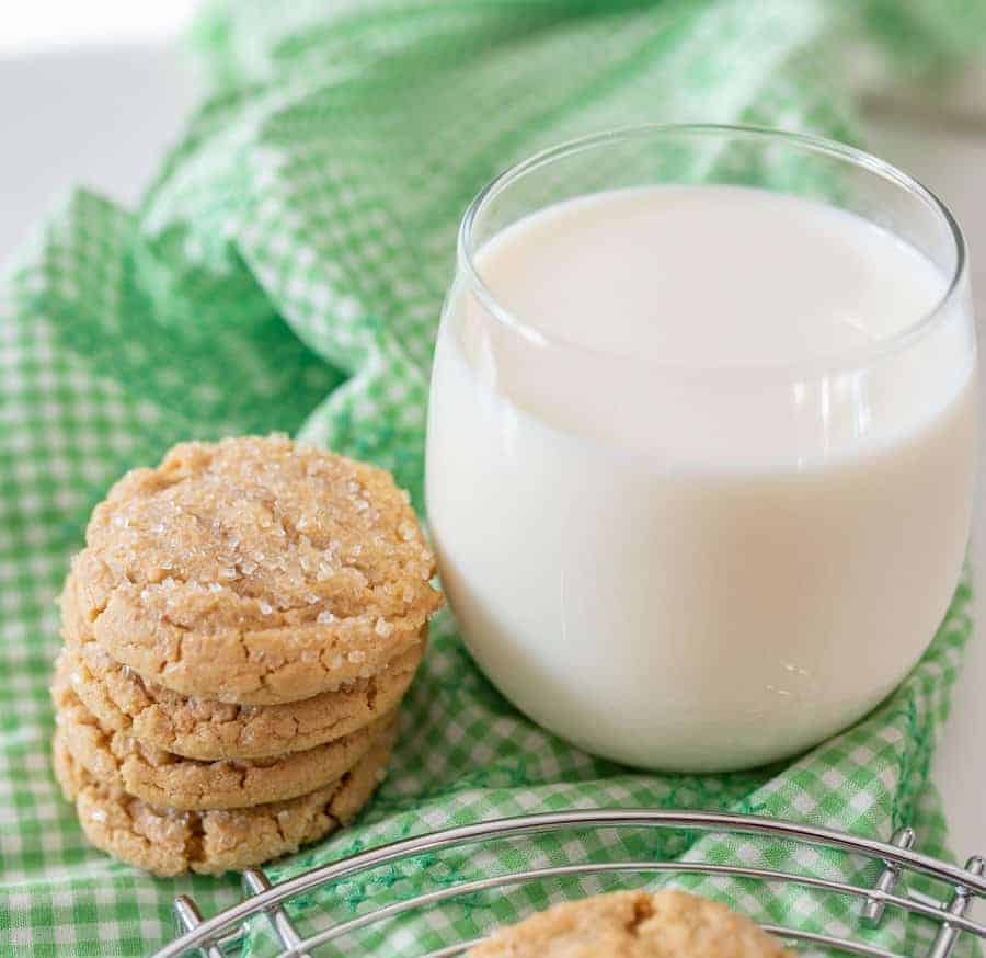 The best peanut butter cookies I've ever eaten because they are so dense and soft and perfectly chewy, resting on a green cloth stacked next to a cup of milk.