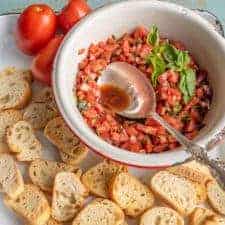 A simple and fresh appetizer, Summer Tomato Bruschetta brings lively flavors of tomato and basil to crunchy, well-buttered slices of toasted baguette.