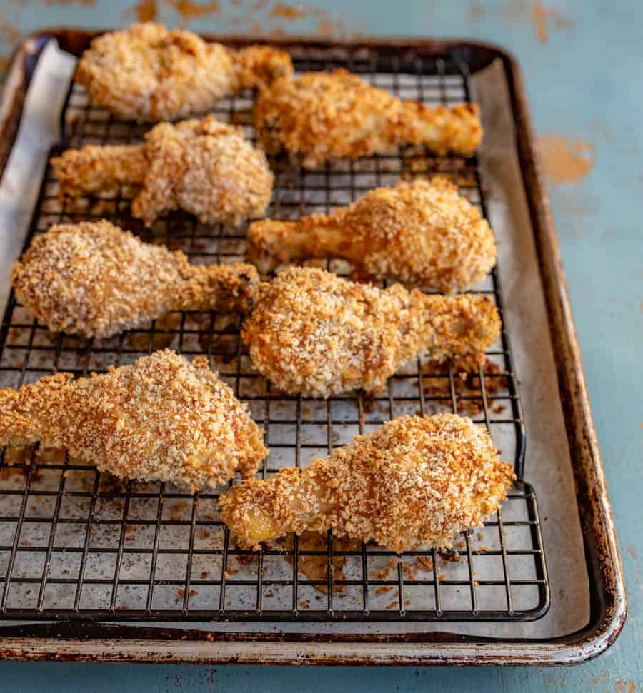 Crispy chicken legs sitting on a black wire baking rack inside of a baking pan.