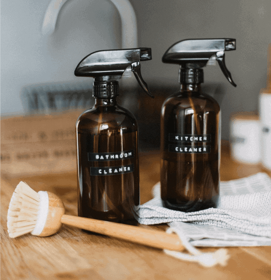 Image of homemade cleaners in dark brown bottles with black handles. 