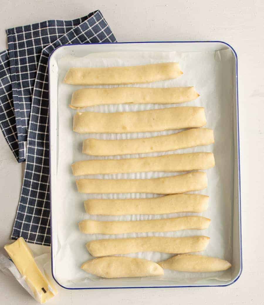 a sheet pan lined with parchment paper containing unbaked breadstick dough.