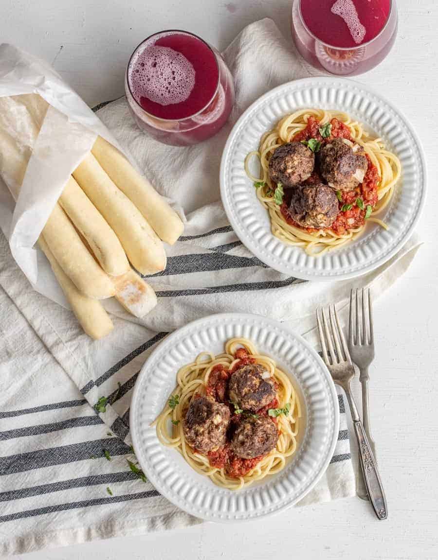 Two plates of homemade sauce and meatballs on top of pasta waiting for someone to enjoy.